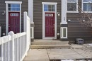 Modern townhouse exterior featuring gray horizontal siding and a striking red paneled entry door - 33 7385 Edgemont Way Nw, Edmonton, AB  - Outdoor 