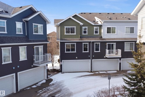 Contemporary townhome exteriors featuring multiple color palettes, attached garages, second-story balconies, white window trim, and dark shingle roofing - 33 7385 Edgemont Way Nw, Edmonton, AB - Outdoor With Facade