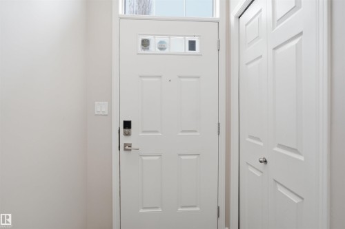 White paneled entry door with transom window, electronic keypad lock, and brushed nickel hardware - 33 7385 Edgemont Way Nw, Edmonton, AB - Indoor Photo Showing Other Room