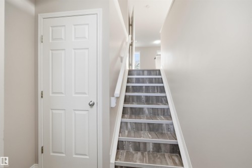 Staircase with wood-finish risers and treads, white balustrade, and light neutral wall paint - 33 7385 Edgemont Way Nw, Edmonton, AB - Indoor Photo Showing Other Room