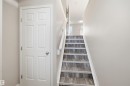 Staircase with wood-finish risers and treads, white balustrade, and light neutral wall paint - 33 7385 Edgemont Way Nw, Edmonton, AB  - Indoor Photo Showing Other Room 