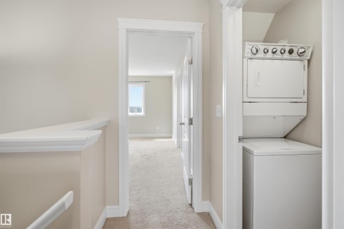 Integrated laundry station with white stacked washer and dryer unit - 19 15151 43 Street, Edmonton, AB - Indoor Photo Showing Laundry Room