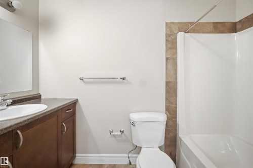 Bathroom featuring a vanity with dark wood-finish cabinetry, a white oval sink, and a dark speckled countertop - 19 15151 43 Street, Edmonton, AB - Indoor Photo Showing Bathroom