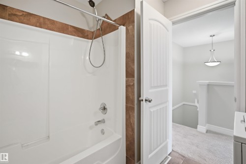 Tub and shower combination featuring a tiled surround and chrome fixtures - 19 15151 43 Street, Edmonton, AB - Indoor Photo Showing Bathroom
