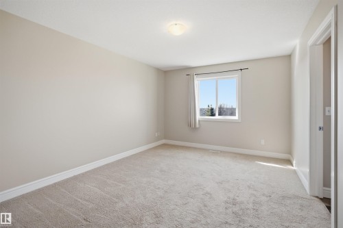 Neutral-toned room featuring light-colored carpet flooring, white baseboards, and a window with white trim - 19 15151 43 Street, Edmonton, AB - Indoor Photo Showing Other Room
