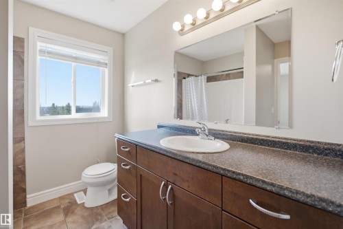 Bathroom featuring a wood-finish vanity with an integrated sink and a speckled countertop - 19 15151 43 Street, Edmonton, AB - Indoor Photo Showing Bathroom