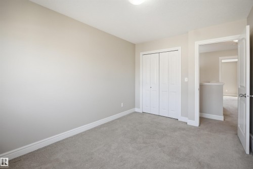 Neutral-toned room featuring light gray carpeting, white trim, and a bi-fold closet with panel doors - 19 15151 43 Street, Edmonton, AB - Indoor Photo Showing Other Room