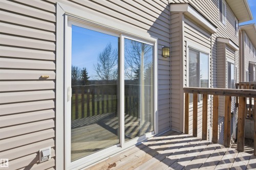 Exterior featuring beige horizontal siding, a sliding glass door, and a wooden deck - 19 15151 43 Street, Edmonton, AB - Outdoor