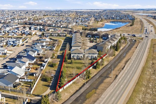 Aerial view of a residential area featuring a body of water with ice, surrounding homes, and a paved roadway - 19 15151 43 Street, Edmonton, AB - Outdoor With View