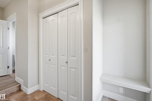 Hallway featuring bi-fold doors with arched panel details, white trim, and a built-in bench - 19 15151 43 Street, Edmonton, AB - Indoor Photo Showing Other Room