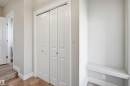 Hallway featuring bi-fold doors with arched panel details, white trim, and a built-in bench - 19 15151 43 Street, Edmonton, AB  - Indoor Photo Showing Other Room 