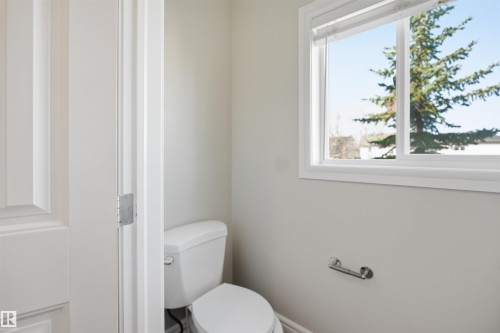 Bathroom with a white toilet, bright window, and neutral wall tones - 19 15151 43 Street, Edmonton, AB - Indoor Photo Showing Bathroom