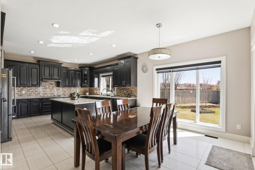 Kitchen and dining area featuring dark cabinetry, a center island with a granite countertop, a tile backsplash, and recessed lighting - 731 57 Street Sw, Edmonton, AB - Indoor