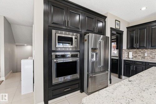 Integrated stainless steel appliances within dark wood-finish cabinetry - 731 57 Street Sw, Edmonton, AB - Indoor Photo Showing Kitchen With Upgraded Kitchen