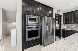 Integrated stainless steel appliances within dark wood-finish cabinetry - 