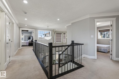 Upper-level landing featuring a black wrought iron railing, light carpet flooring, recessed lighting, and white trim - 731 57 Street Sw, Edmonton, AB - Indoor Photo Showing Other Room