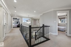 Upper-level landing featuring a black wrought iron railing, light carpet flooring, recessed lighting, and white trim - 