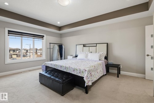 Carpeted interior space featuring a tray ceiling with recessed lighting and a large window with white trim - 731 57 Street Sw, Edmonton, AB - Indoor Photo Showing Bedroom