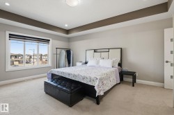 Carpeted interior space featuring a tray ceiling with recessed lighting and a large window with white trim - 