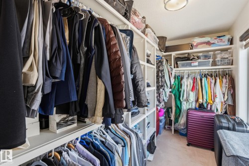 Custom closet system featuring multiple hanging rods, integrated shelving, and a neutral carpeted floor - 731 57 Street Sw, Edmonton, AB - Indoor With Storage