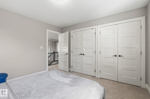 Bedroom featuring multiple storage closets with modern panel doors, neutral carpeting, and light gray wall paint - 731 57 Street Sw, Edmonton, AB - Indoor Photo Showing Bedroom