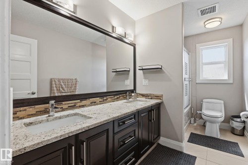 Double vanity with granite countertop, integrated rectangular sinks, and dark wood cabinetry - 731 57 Street Sw, Edmonton, AB - Indoor Photo Showing Bathroom