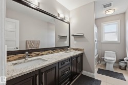 Double vanity with granite countertop, integrated rectangular sinks, and dark wood cabinetry - 