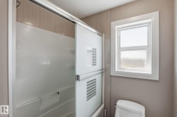 Shower enclosure with sliding frosted glass doors, a white acrylic shower surround, and light-toned tile accents - 