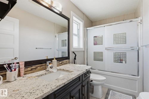 Bathroom featuring a white vanity with a granite-style countertop and a rectangular undermount sink - 731 57 Street Sw, Edmonton, AB - Indoor Photo Showing Bathroom