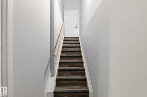 Staircase featuring wood-finish treads with dark risers, a light wood-tone handrail, and white side stringers - 731 57 Street Sw, Edmonton, AB - Indoor Photo Showing Other Room