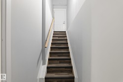 Staircase featuring wood-finish treads with dark risers, a light wood-tone handrail, and white side stringers - 