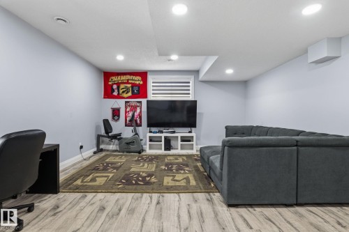 Open-concept recreation room featuring wood-finish flooring, recessed lighting, and light gray wall paint - 731 57 Street Sw, Edmonton, AB - Indoor