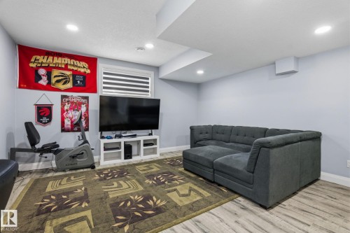 Spacious lower-level room featuring light wood-finish flooring, recessed ceiling lighting, and a window with horizontal blinds - 731 57 Street Sw, Edmonton, AB - Indoor