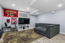 Spacious lower-level room featuring light wood-finish flooring, recessed ceiling lighting, and a window with horizontal blinds - 