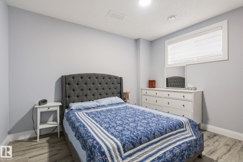 Spacious bedroom featuring light gray walls, wood-finish flooring, and a large window with white trim - 731 57 Street Sw, Edmonton, AB - Indoor Photo Showing Bedroom