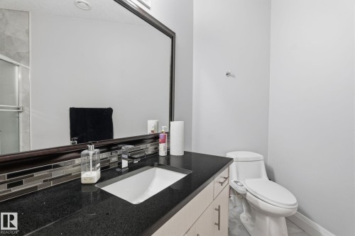 Vanity featuring a dark countertop with an integrated sink and modern chrome faucet - 731 57 Street Sw, Edmonton, AB - Indoor Photo Showing Bathroom