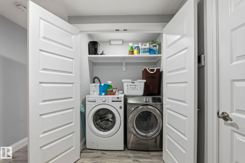 Dedicated laundry closet featuring a white front-load washer, a stainless steel front-load dryer, and integrated shelving - 731 57 Street Sw, Edmonton, AB - Indoor Photo Showing Laundry Room