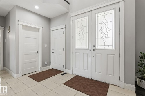Entryway featuring double doors with decorative glass panels, light tile flooring, and crisp white trim - 731 57 Street Sw, Edmonton, AB - Indoor Photo Showing Other Room