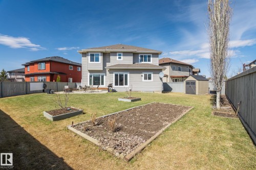 Expansive backyard featuring a manicured lawn, a large patio area with direct access to the interior, and a dedicated garden bed - 731 57 Street Sw, Edmonton, AB - Outdoor