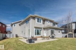 Spacious backyard featuring a concrete patio, well-maintained lawn, and a storage shed - 