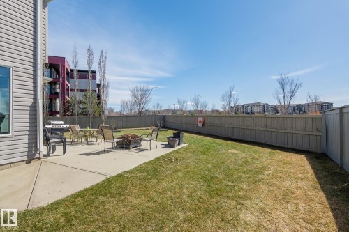 Expansive backyard featuring a concrete patio, a manicured lawn, a full wood privacy fence, and a vinyl-sided exterior wall - 731 57 Street Sw, Edmonton, AB - Outdoor