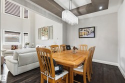 Formal dining area featuring a tiered ceiling with recessed lighting and a crystal chandelier - 