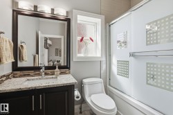 Bathroom featuring a dark wood vanity with a light-colored speckled countertop, an undermount sink, and a tiled backsplash - 