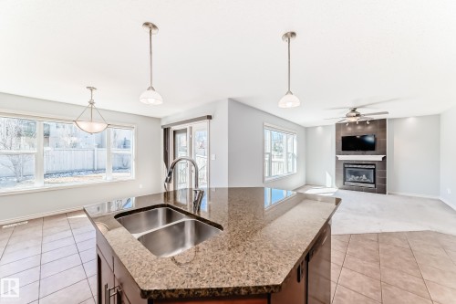 Kitchen island with an undermount double basin sink and a stone-finish countertop - 6723 19 Avenue, Edmonton, AB 