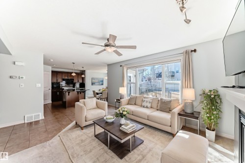Open-concept living area featuring light-toned walls, a ceiling fan, and large sliding glass doors - 6723 19 Avenue, Edmonton, AB 