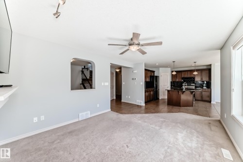 Open-concept living space featuring light gray walls, carpet flooring, and a ceiling fan with integrated lighting - 6723 19 Avenue, Edmonton, AB 