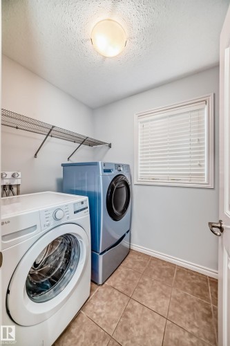 Laundry area featuring tile flooring, a window with horizontal blinds, built-in wire shelving, and a ceiling-mounted light fixture - 6723 19 Avenue, Edmonton, AB 