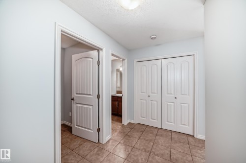 Hallway featuring light blue walls and brown square tile flooring - 6723 19 Avenue, Edmonton, AB 