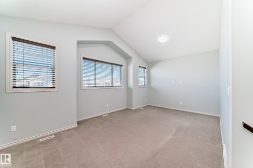 Spacious room featuring vaulted ceilings, light gray wall paint, and plush carpeting - 6723 19 Avenue, Edmonton, AB 
