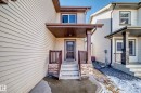 Covered entryway featuring a dark wood-finish door, stone-accented pillars, and matching wood-finish railings - 6723 19 Avenue, Edmonton, AB 
